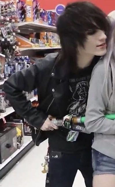 two people are standing in a store with their arms around each other and one is holding a bottle