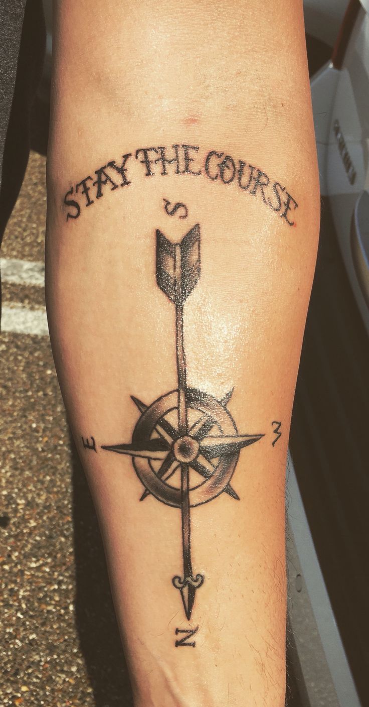 a man with a compass tattoo on his leg that says stay the course and an arrow