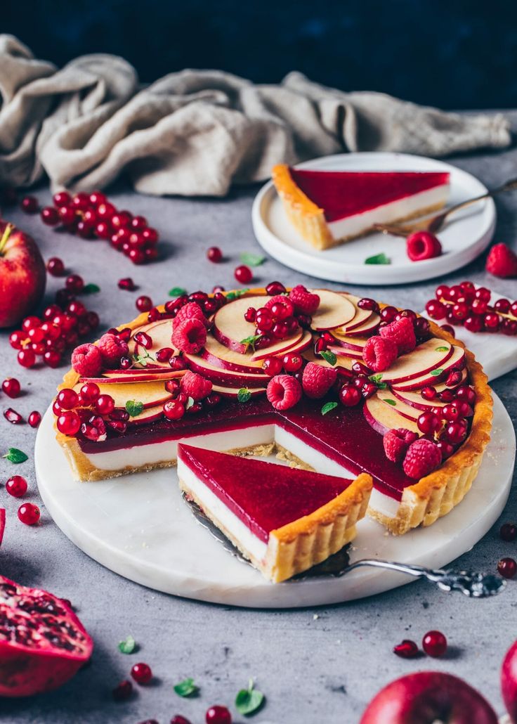 a slice of cheesecake with raspberry topping on a plate next to the rest of the pie