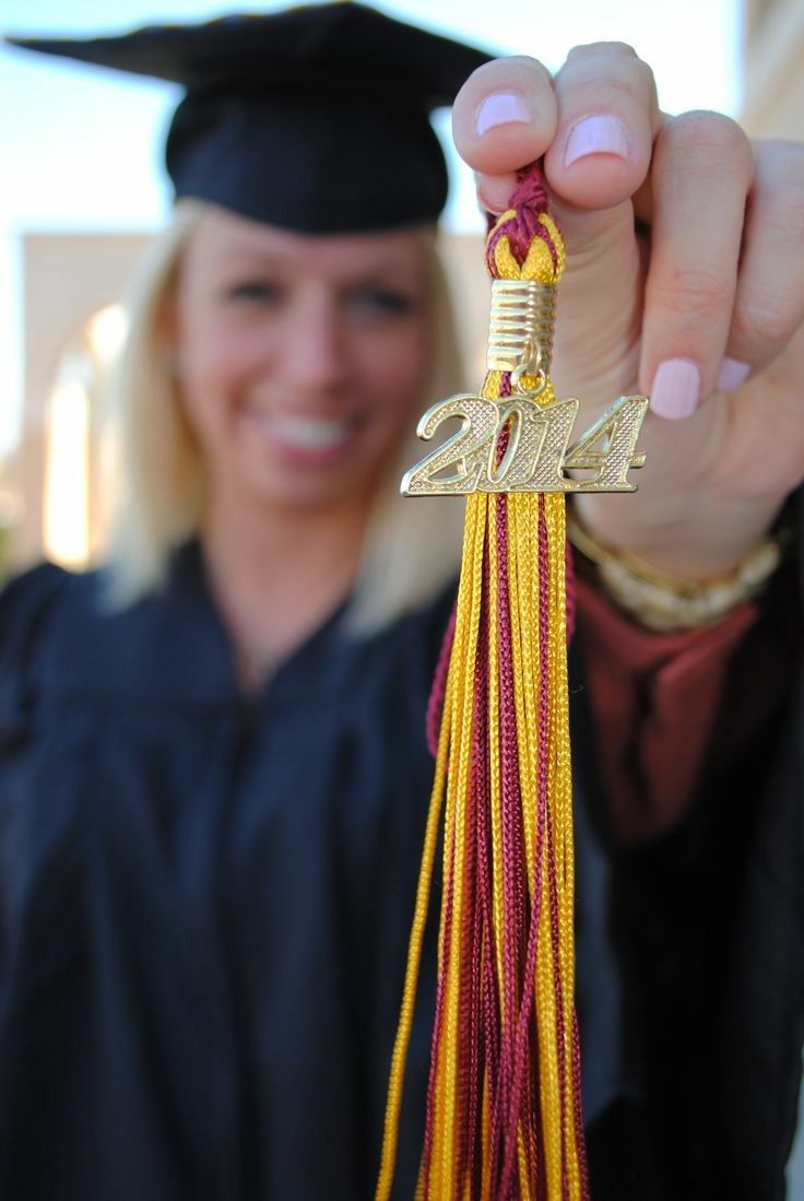 a woman in graduation cap and gown holding up a tassel with the number twenty four on it