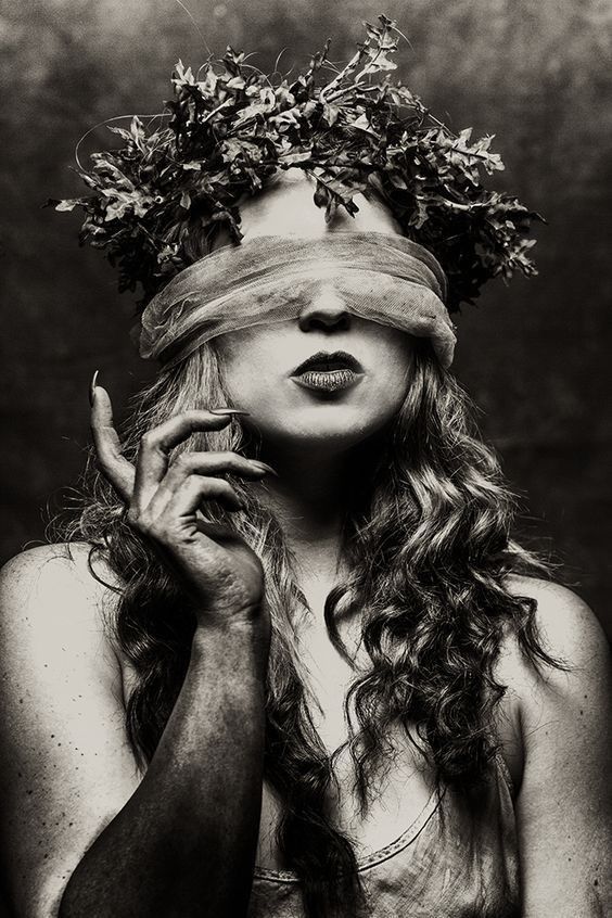 black and white photograph of a woman with flowers on her head, covering her eyes