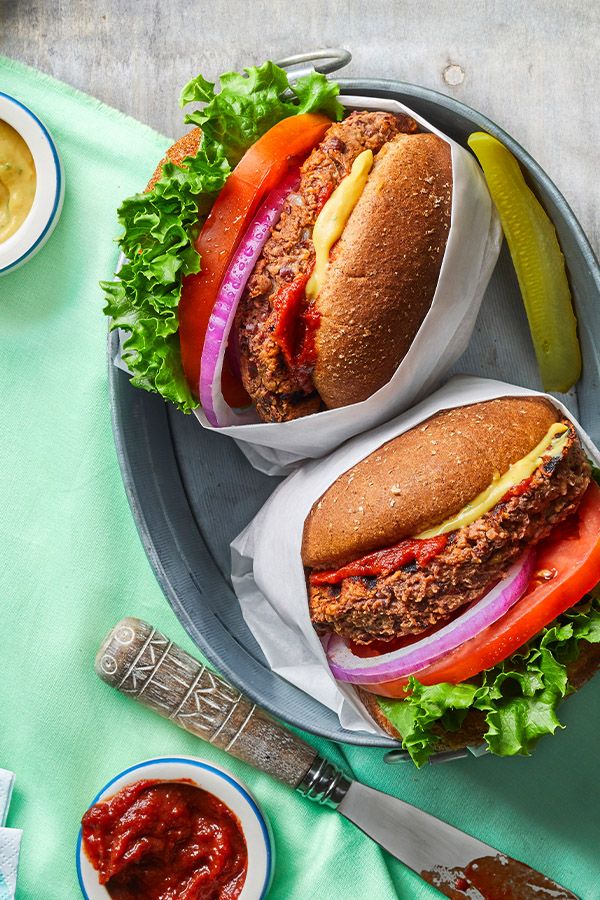 two hamburgers with lettuce, tomato and pickle slices on a plate