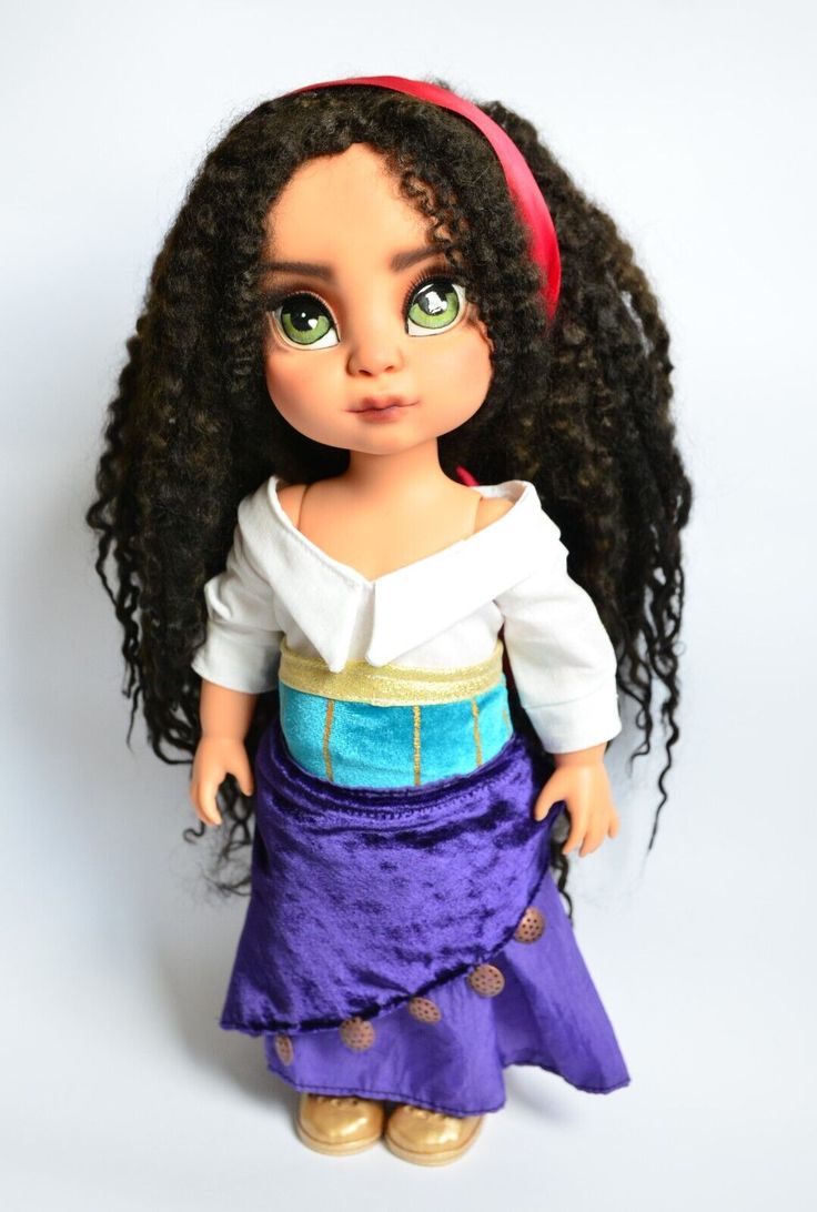 a doll with long black hair wearing a purple dress and red headband, standing on a white background