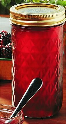 a glass jar filled with red liquid next to a bowl of cranberry sauce