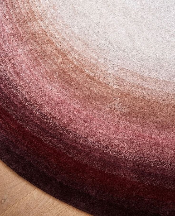 an area rug with red and white colors on top of wooden floor next to wood table