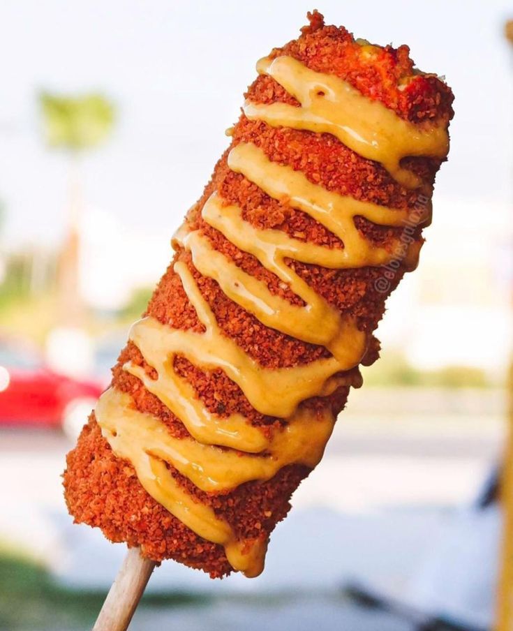 a skewer filled with meat covered in sauce and drizzled with mustard