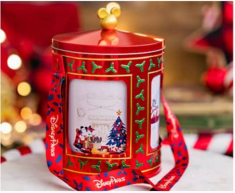 a red tin can with christmas decorations on it and a ribbon around the top that is attached to an ornament