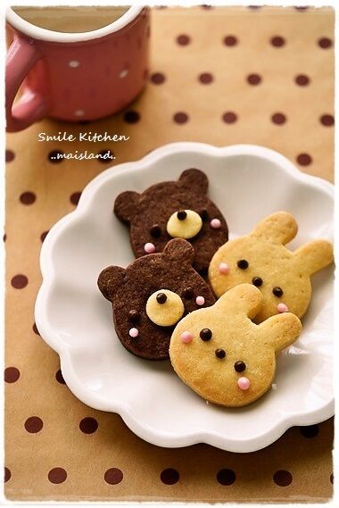 some cookies in the shape of teddy bears are on a plate next to a cup