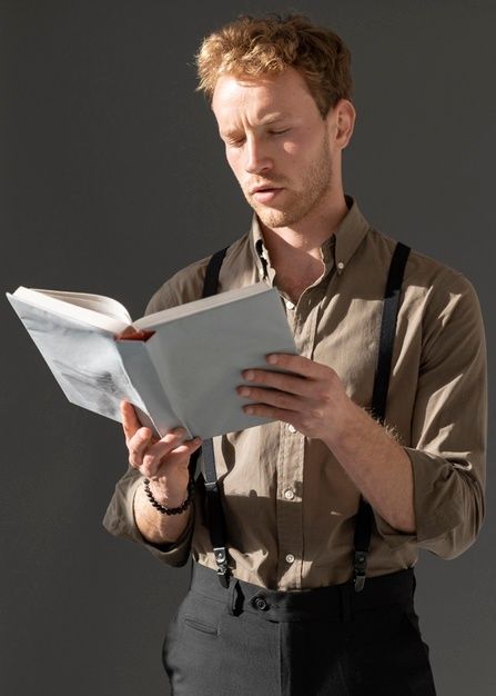 a man in suspenders reading a piece of paper