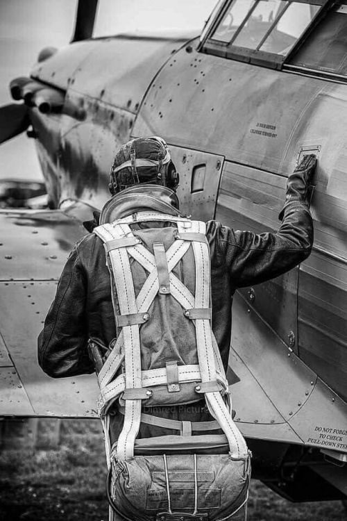 black and white photograph of a man standing in front of an airplane with his back to the camera