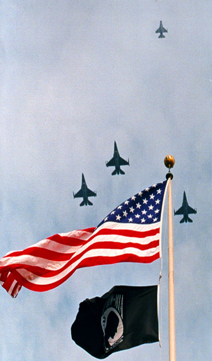 an american flag flying in front of fighter jets