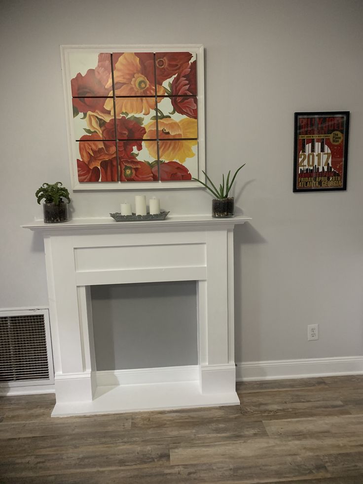 a white fireplace with a painting on the wall above it