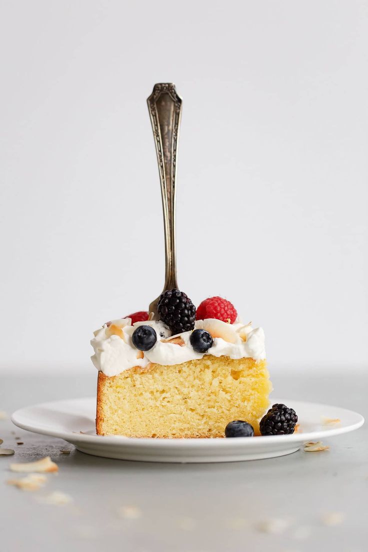 a piece of cake with berries and whipped cream on top