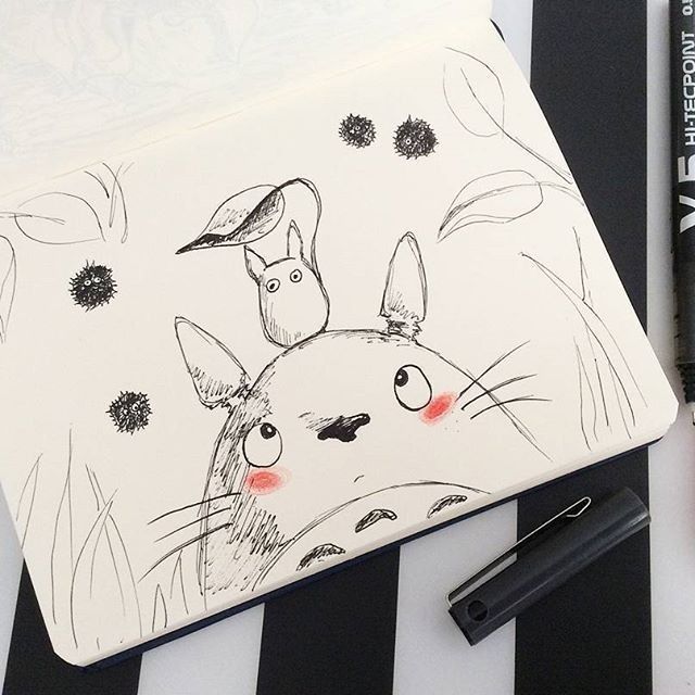 a pencil drawing of a rabbit and bird on a white paper with black marker pens next to it