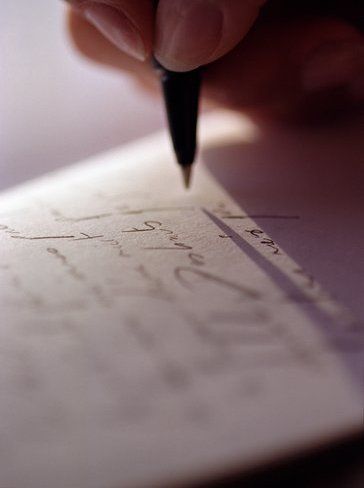 a person is writing on a piece of paper with a pen in their left hand