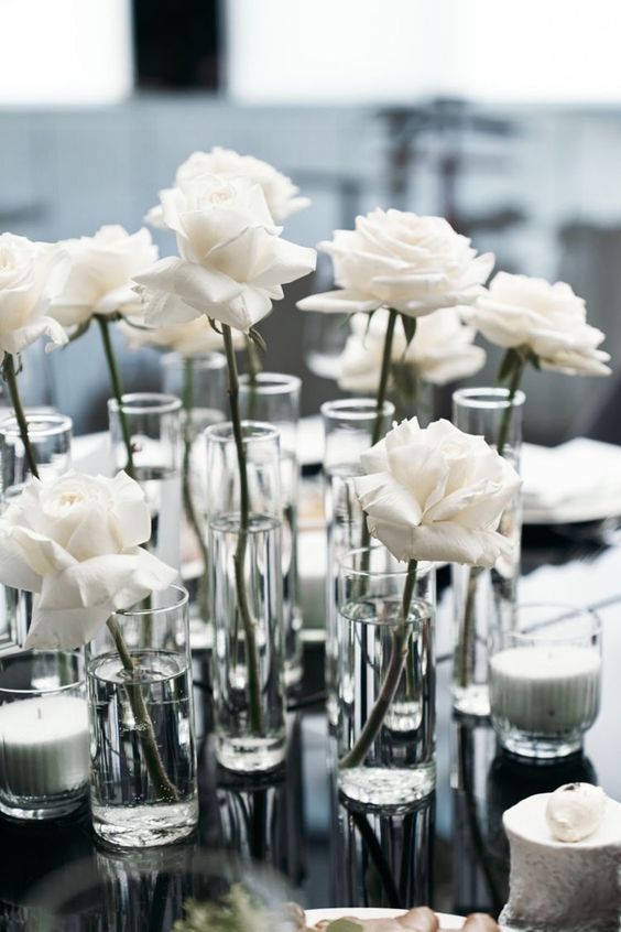 there are many vases with white flowers in them on the dining room table together