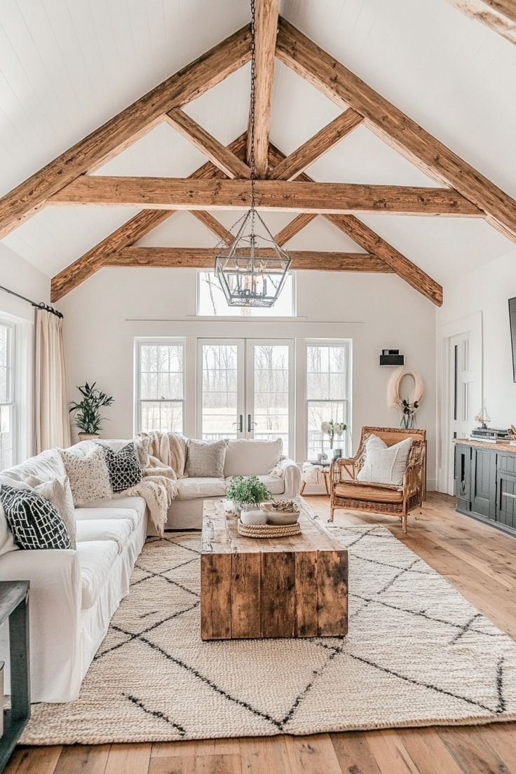 a living room filled with furniture and a large wooden beam ceiling over a white couch