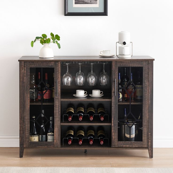 a wooden cabinet with wine bottles and glasses on it in front of a white wall