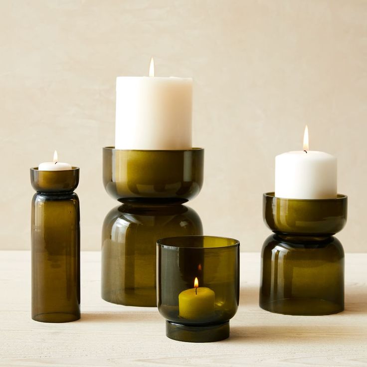 three green glass candle holders sitting on top of a table