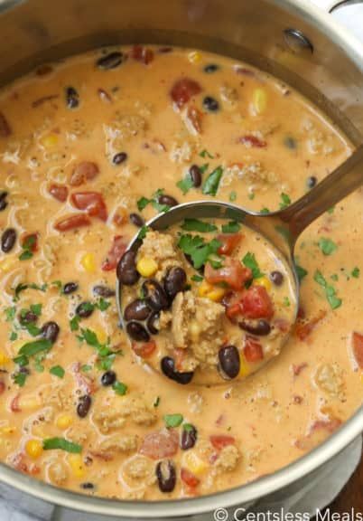 a ladle full of mexican chicken soup with beans and corn