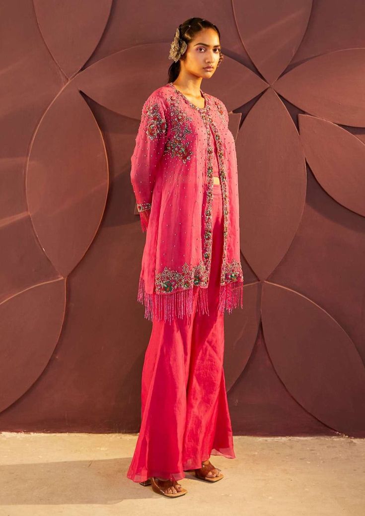 Editor's Note Featuring Fuschia Fleur embroidered jacket with flared pants carrying work thread embroidery. Color: Pink Fabric: Silk organza, lace, lining: satin Embroidery details: Zari And dabka Fit: Fitted at bust for inner Neck type: Round neck Component: Jacket, pants and inner Occasion: Dinner party and engagement Care: Dry clean only Note: Can be customised in any color from designers color palette About the Designer Parul and Preyanka interplay of subtle tones, weaved with the floral ins Traditional Embellished Pant Set For Spring, Spring Silk Embroidered Pant Set, Eid Silk Pants With Embroidery, Pink Pants For Wedding Eid Festival, Silk Embroidered Pants For Eid, Embellished Pant Set For Wedding, Embellished Pant Set For Spring Wedding, Spring Wedding Embellished Pant Set, Eid Party Pant Set With Floral Embroidery