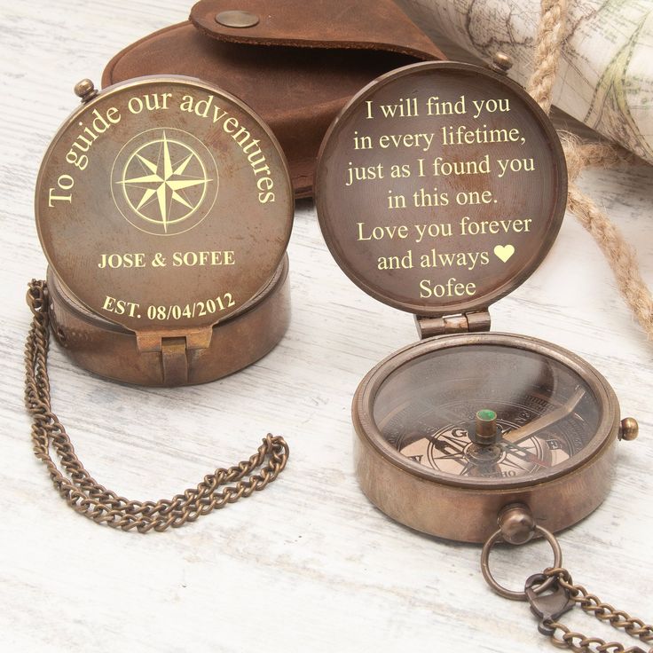 two personalized pocket watches sitting next to each other on a white table with a brown bag