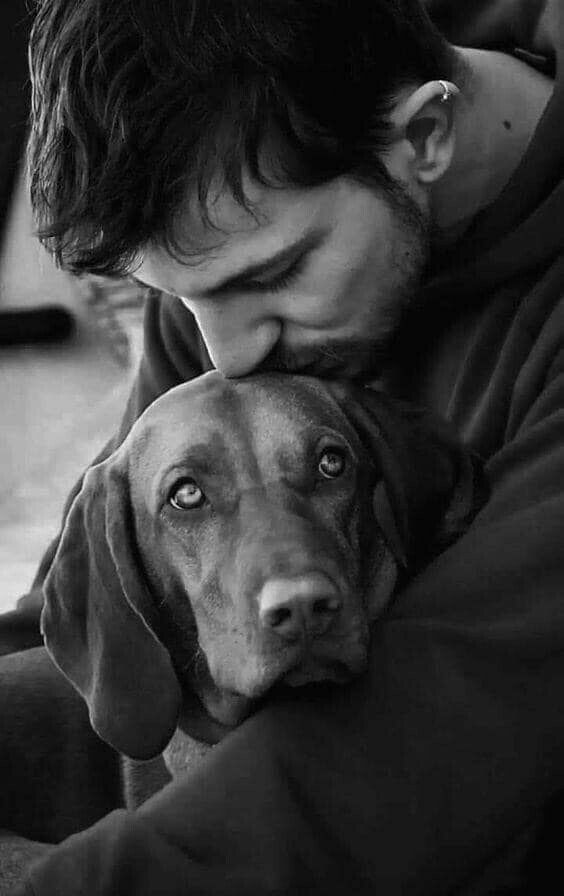 a man is hugging his dog while he looks at the camera with an intense look on his face