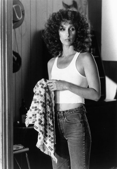 black and white photograph of a woman with curly hair holding a jacket in her hand