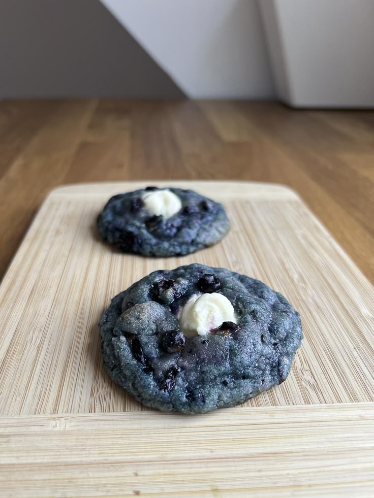 two blueberry cookies on a cutting board with butter