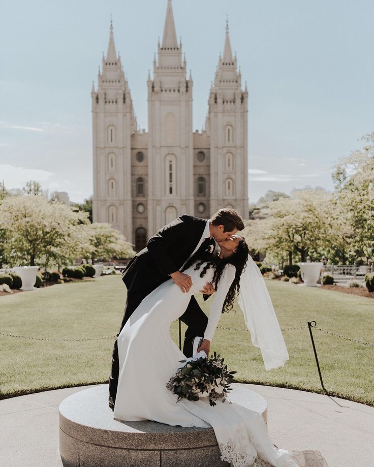 a bride and groom kissing in front of the salt lake temple on their wedding day