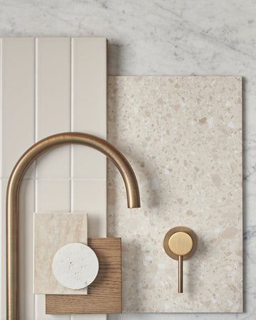 a bathroom with marble tiles and brass faucet on the wall next to a soap dispenser