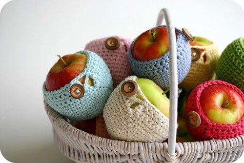 a basket filled with crocheted apples sitting on top of a table