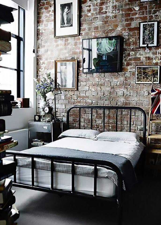 a bedroom with a brick wall and metal bed frame