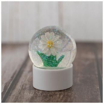 a snow globe with a flower inside on a wooden table