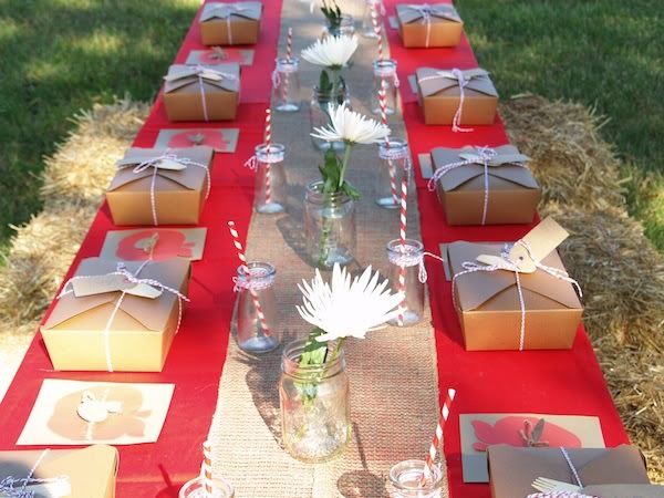 a long table is set up with many boxes and flowers in vases on it