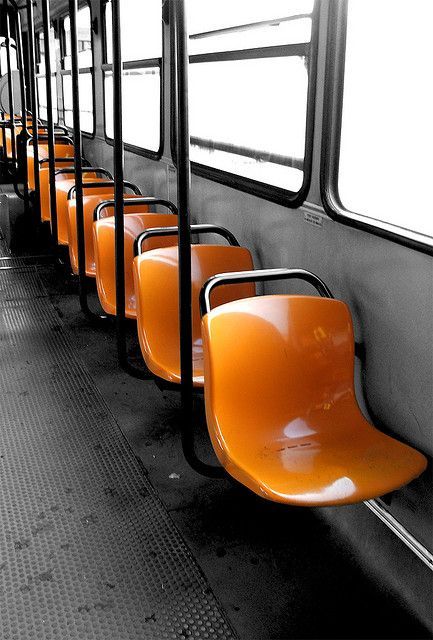 orange seats are lined up on the side of a subway car in black and white