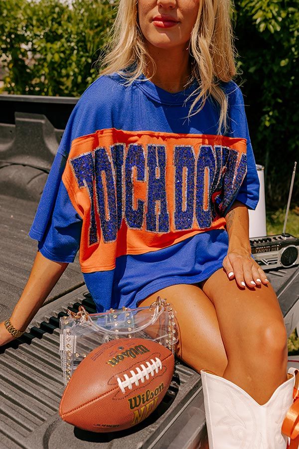 - Show off your team spirit in this dazzling oversized 'TOUCHDOWN' tee! Featuring a sequined design and chic unfinished seam accents, you'll shine on game day. Show your team spirit with our vibrant clothing collection inspired by the bold colors of popular college football teams like the Auburn Tigers and the University of Florida Gators. - Unlined lightweight material with unfinished seam accents - A sequined 'TOUCHDOWN' design across the front - Short drop sleeves - An oversized silhouette that ends in an unfinished hemline - This piece is perfect for fans of Auburn, Florida, Virginia, and more! Auburn College Football Game Outfit, Nationals Cheer Shirts, College Football Outfits For Women, Game Day Fits Football, Florida Gators Gameday Outfits, Boyfriend Football Shirts Girlfriends, Cute Football Outfits For Women, High School Spirit Shirts, Cute Football Outfit