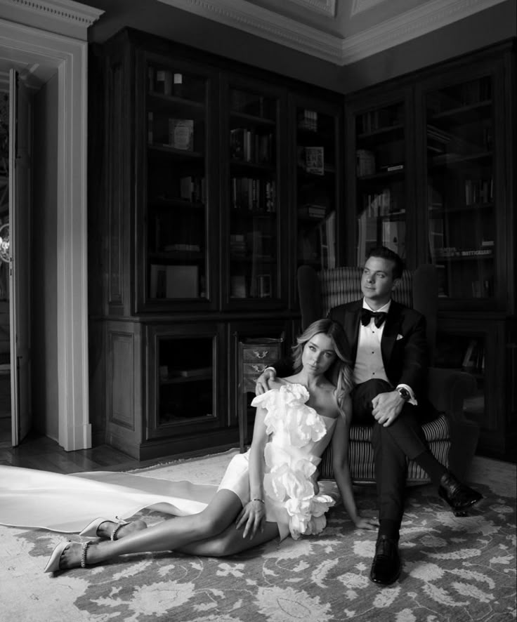 a man sitting next to a woman on the floor in front of a bookcase