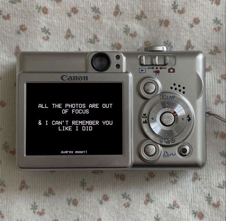 a digital camera sitting on top of a bed next to a flowered sheet with the words, all the photos are out of focus and i can't remember you like it