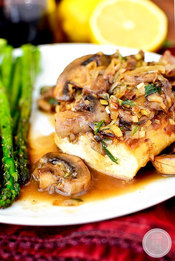 a white plate topped with chicken, mushrooms and asparagus