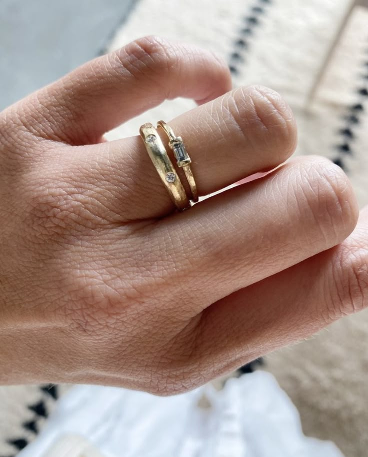 a person's hand with a gold ring on it and two diamonds in the middle