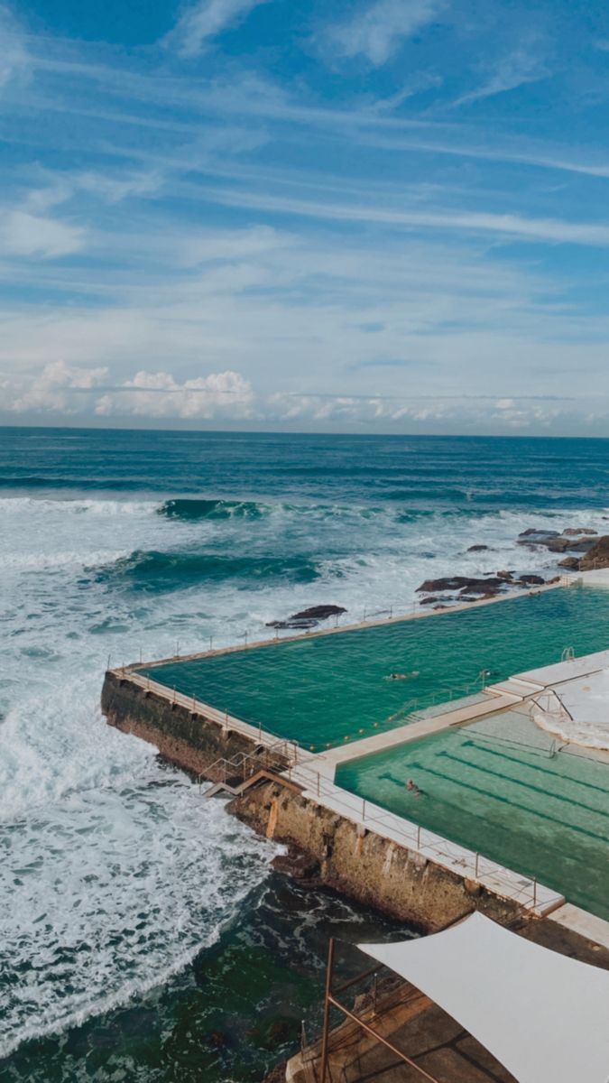 an outdoor swimming pool next to the ocean