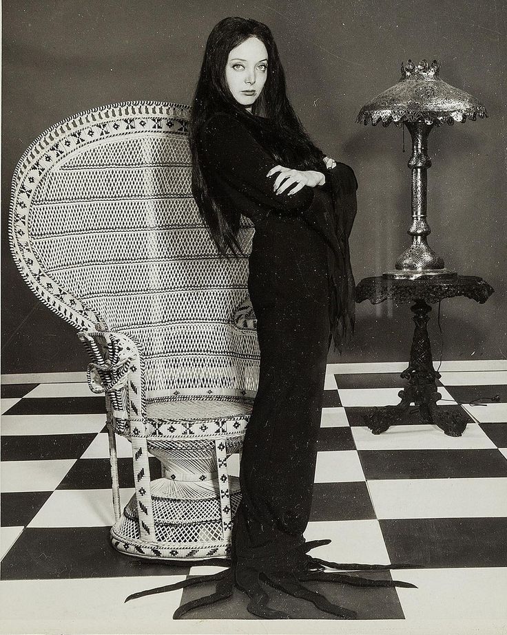 a woman standing next to a chair on a checkered floor