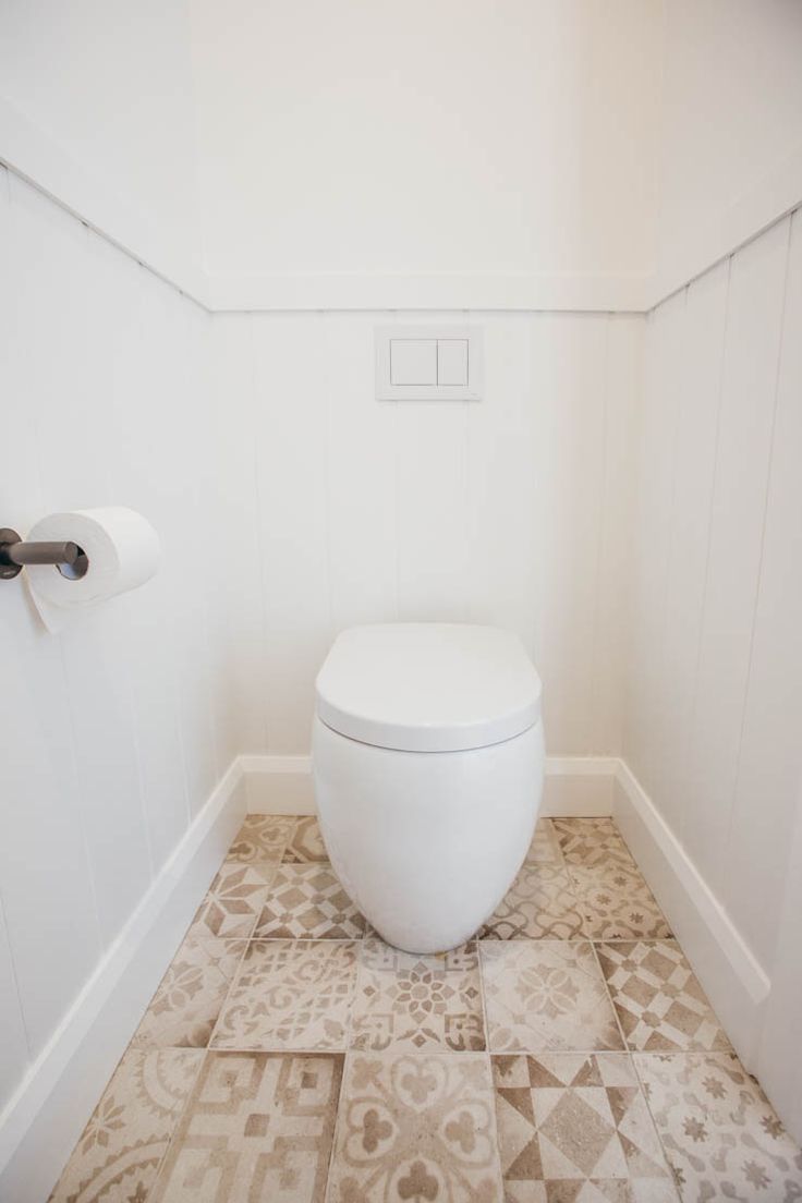 a white toilet sitting in a bathroom next to a roll of toilet paper on the wall