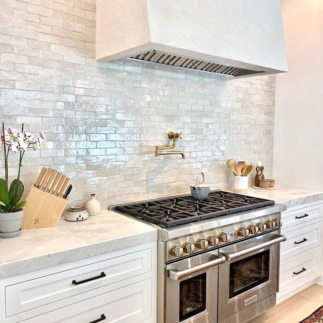 a stove top oven sitting inside of a kitchen next to white cabinets and counter tops