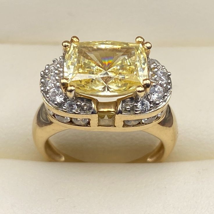 For Sale, A Stunning And Rare Yellow Tourmaline (3.49 Carats Main Stone) 14 Karat Yellow Gold Ring. Size: 5 Weight: 5.85 Grams Tourmaline: Radiant Cut, Rectangular, 8 Prong Held, Measuring 10 Mm Long X 8 Mm Wide For A Weight Of 3.49 Carats. Tourmaline: 2 Small Square Cut Stones, Bezel Held, Measuring 2 Mm Diameter (Total Of 0.12 Carats) Cubic Zirconia: Round, Prong And Bezel Set, Measuring 1.5 Mm Diameter, 24 Stones (0.36 Carats) Band Width Narrowest: 2 Mm Band Width Widest (Top Of Ring): 9.16 M Yellow Topaz Center Stone Ring In 14k Gold, Fine Jewelry Yellow Topaz Ring With Halo Setting, Yellow Topaz Ring With Halo Setting, Yellow Topaz Halo Ring Fine Jewelry, Formal Yellow Topaz Ring With Accent Stones, Elegant Yellow Sapphire Ring For Anniversary, Dazzling Yellow Rings With Halo Setting, Yellow Topaz Ring With Center Stone For Formal Occasions, Yellow Gold Radiant Cut Sapphire Ring With Center Stone