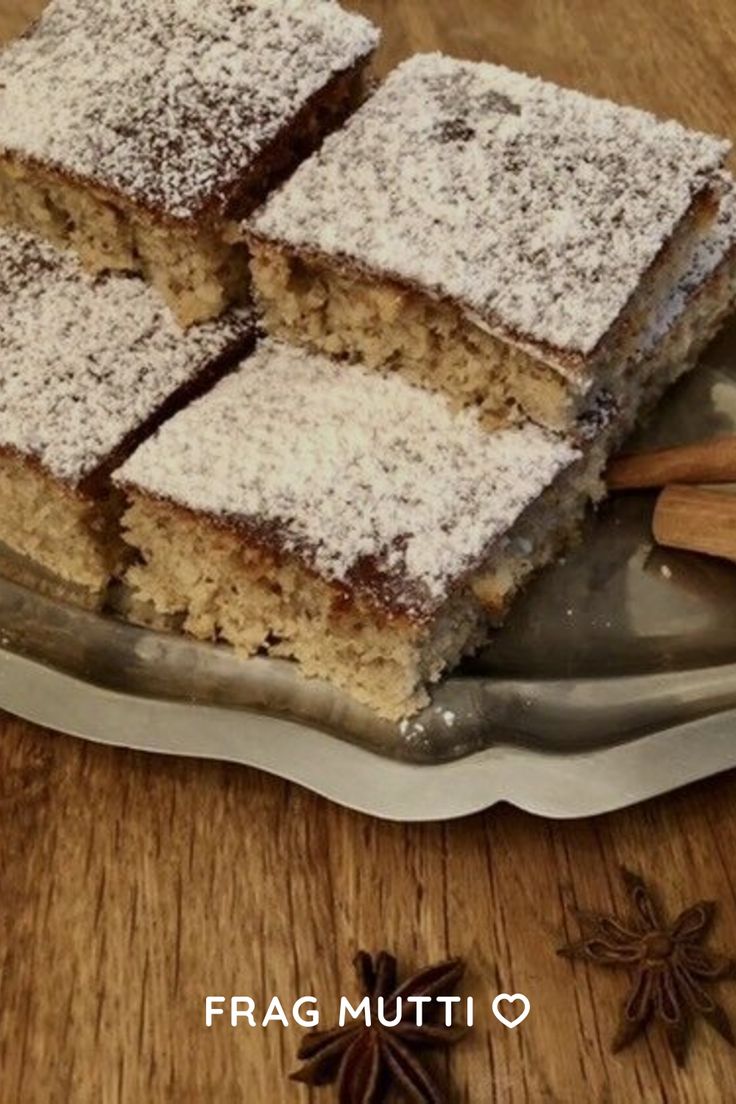 four pieces of cake sitting on top of a silver plate next to cinnamon sticks and star anise