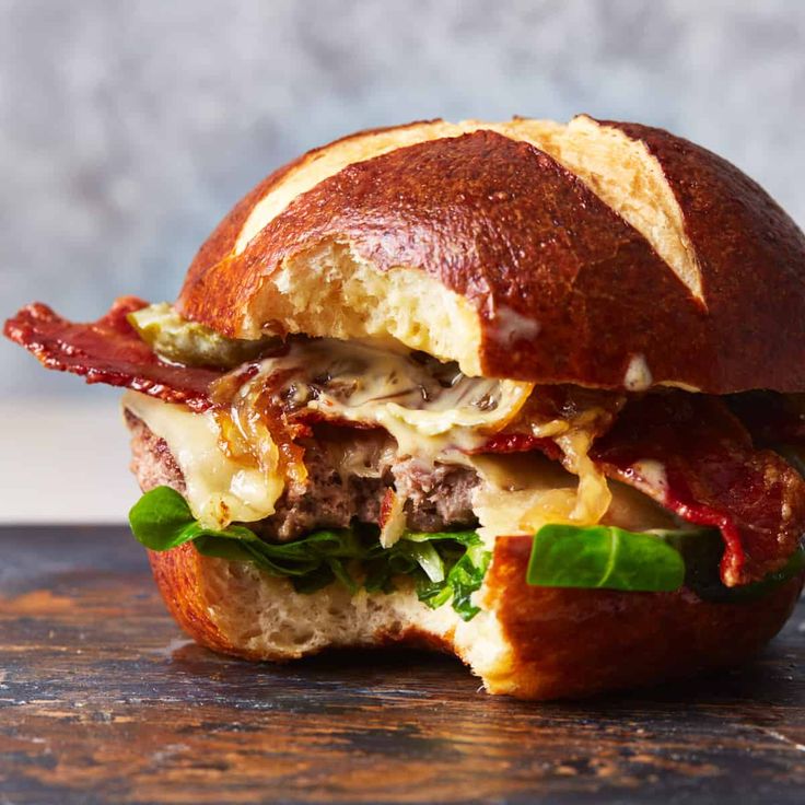 a close up of a sandwich with meat and cheese in it on a wooden table