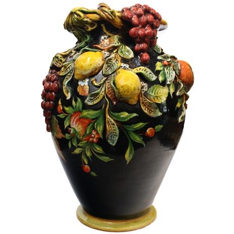 a black vase with fruit and leaves painted on it