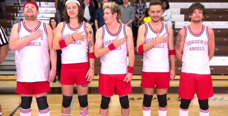 a group of men standing next to each other on top of a basketball court in red and white uniforms